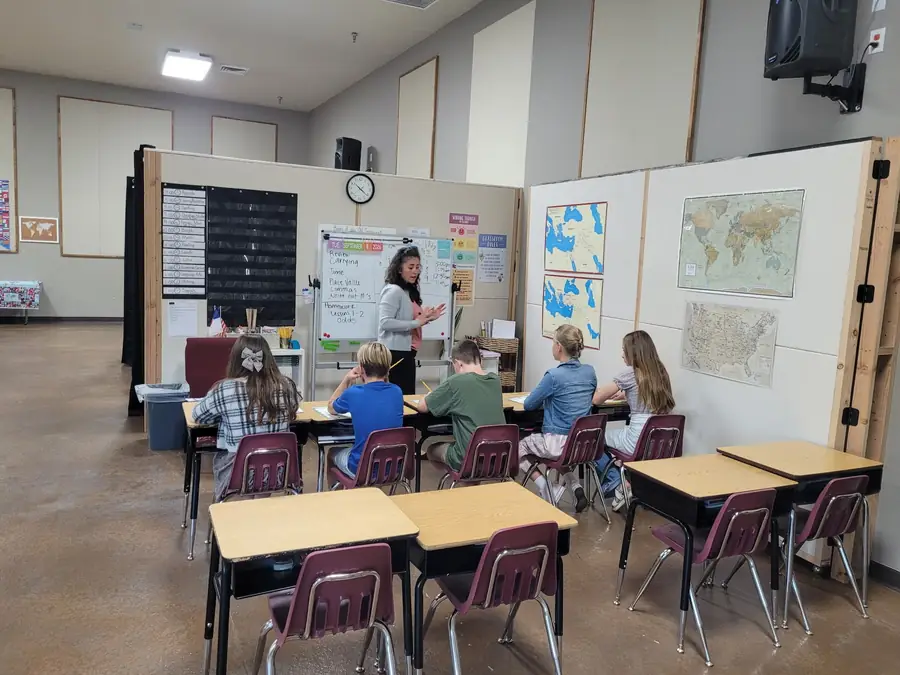 A teacher explaining a math review at the whiteboard to Cornerstone students seated at their desks