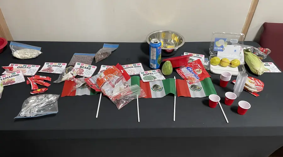 A tasting table from a Missionaries in Training lesson on Mexico, with labeled foods and small Mexican flags